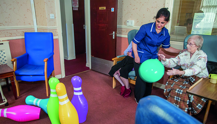A carer and a resident playing with bright skittles
